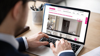 Mann sitzt vor einem Laptop und sieht sich ein Immobilieninserat an