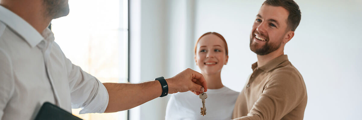 Vermieter übergibt Schlüssel an Paar in Wohnung