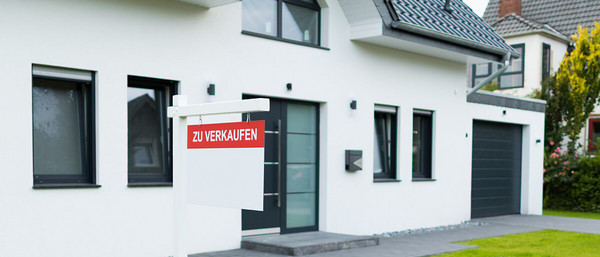 Mann hält Energieausweis in den Händen vor Haus