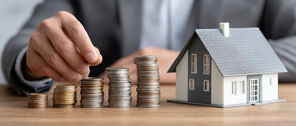Modellhaus auf Tisch mit Münzen