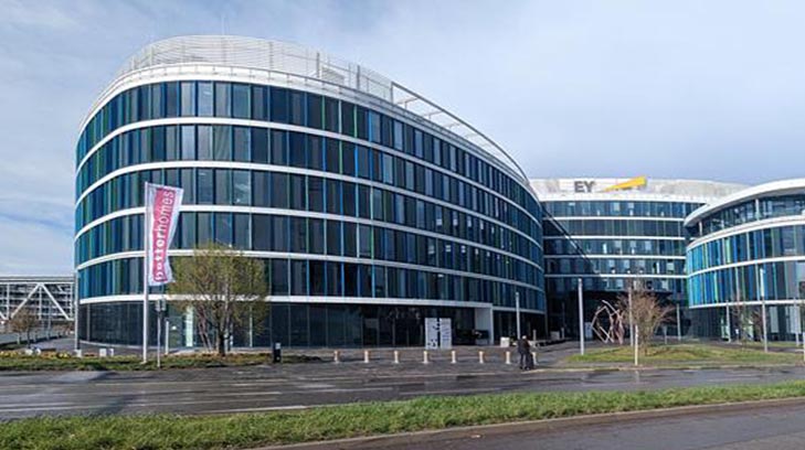 Verglastes Bürogebäude mit Hochhaus im Hintergrund
