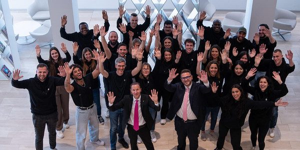 Mehrere Mitarbeitenden strecken lachend die Hände in die Luft