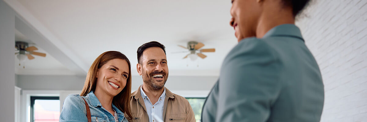 Paar in Wohnung lacht und schüttelt Frau die Hand