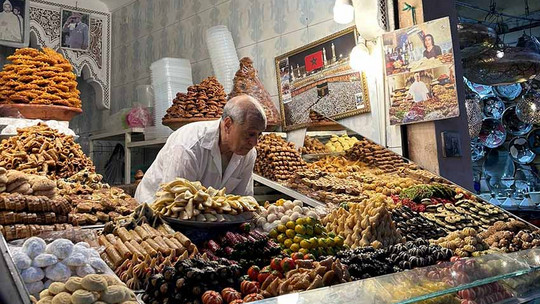 Marktstand mit älterem Herr and der Kasse und vielen verschiedenen Früchten