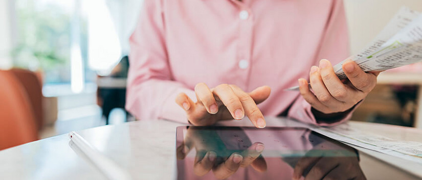 Frau sitzt am Tisch und rechnet etwas zusammen