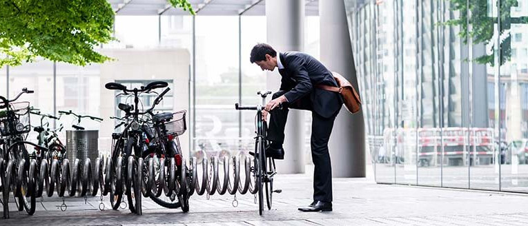 Mann in Anzug steht vor seinem Fahrrad